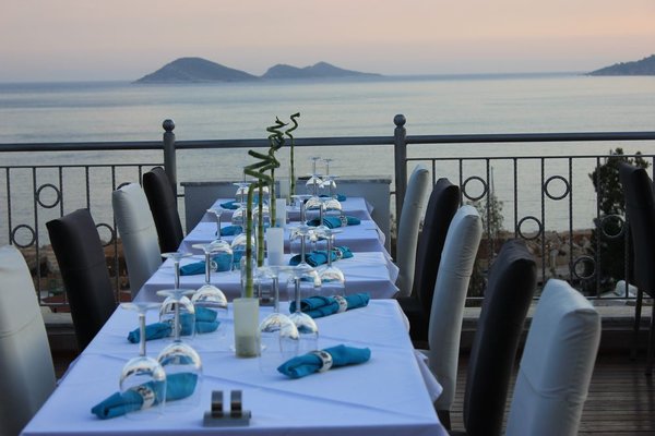 two tables set for fine dining on rooftop sea in background