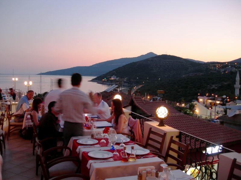 waiter serves table on rooftop mountains and sea in background